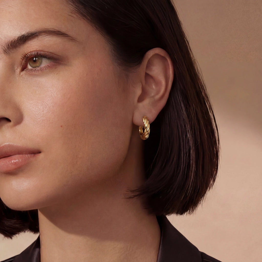 Close-up of a woman wearing a gold hoop earring against a neutral background